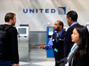 Airpot workers speak to a passenger inside the United Airlines terminal  at O'Hare International Airport in Chicago.