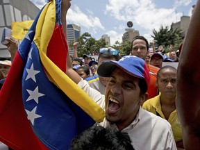 An opposition member waves a Venezuelan flag as National Assembly President Julio Borges speech during a special public session at a square in Caracas, Venezuela, Saturday, April 1, 2017. Venezuela's president and Supreme Court backed down Saturday from an audacious move to strip congress of its legislative powers that had sparked widespread charges that the South American country was no longer a democracy.