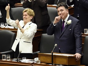 Ontario Finance Minister Charles Sousa, right, and Premier Kathleen Wynne get a standing ovation after announcing free universal health care to everyone over the age of 24 as part of the 2017 Ontario budget at Queen's Park in Toronto on Thursday, April 27, 2017.
