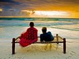 A couple enjoys a breathtaking sunset as the tepid waters of the Indian Ocean wash upon a tropical beach in Zanzibar.