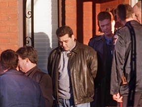 Angelo Musitano, centre, is led from home by police after being charged in the murder of mob boss Johnny Papalia.