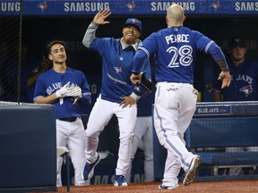 Steve Pearce is congratulated at the Blue Jays dugout by Marcus Stroman after scoring a run in the second inning of their game against the Seattle Mariners at Rogers Centre in Toronto on Friday night.