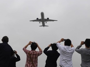 Spectators take photos as they watch the Comac C919, China's first large passenger jet, coming in for a landing on its maiden flight at Shanghai's Pudong airport