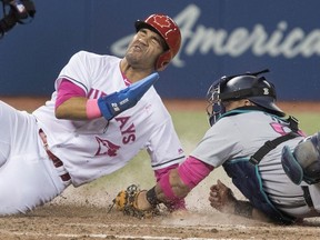 The Blue Jays' Devon Travis scores on a double steal, beating the tag attempt by Mariners catcher Carlos Ruiz in the eighth inning on Saturday, May 13, 2017 at the Rogers Centre.