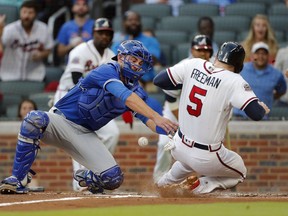 Freddie Freeman of the Braves scores on a Nick Markakis two-run single as the ball gets away from Toronto Blue Jays catcher Luke Maile in the first inning of their game Wednesday night in Atlanta.