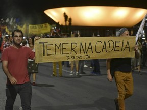 Demonstrators carry a sign that reads in Portuguese "Temer in jail" to protest Brazil's President Michel Temer in Brasilia, Brazil, Thursday, May 18, 2017. The embattled Brazilian leader says he will fight allegations that he endorsed the paying of hush money to an ex-lawmaker jailed for corruption.