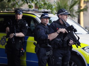 Armed police at the scene during a vigil in Albert Square, Manchester, England, Tuesday May 23, 2017, the day after the suicide attack at an Ariana Grande concert that left 22 people dead