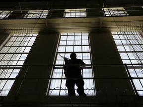 In this Aug. 16. 2016, file photo, a guard stands watch over the east block of death row at San Quentin State Prison in San Quentin, Calif.