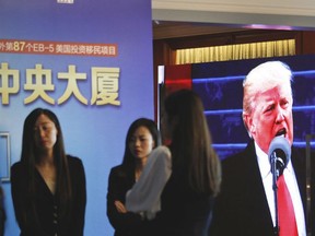 A projector screen shows a footage of U.S. President Donald Trump as workers wait for investors at a reception desk during an event promoting EB-5 investment in a Kushner Companies development at a hotel in Shanghai, China, Sunday, May 7, 2017.