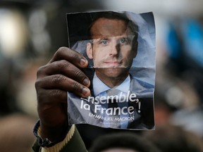 Supporters of Emmanuel Macron hold up his photo outside his campaign headquarters in Paris, on Sunday.