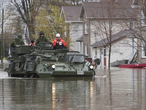 A military vehicle drives along a flooded street Sunday May 7, 2017 in Gatineau, Que.