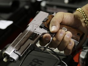 A customer looks at a SIG Sauer hand gun at a gun show held by Florida Gun Shows, Saturday, Jan. 9, 2016, in Miami