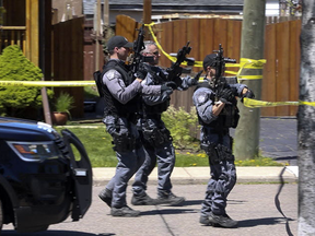 Heavily armed tactical officers near the site of a home invasion and shooting, in Hamilton, Ont.
