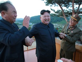 This picture taken on May 14, 2017 and released on May 15 shows North Korean leader Kim Jong-Un (2nd L) reacting during a test launch of a ground-to-ground medium long-range strategic ballistic rocket Hwasong-12 at an undisclosed location.