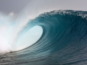 A surfing wave breaks over coral reef in the Mentawai Island, Sumatra, Indonesia.