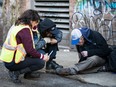 Supervisors with DTES Markets attend to a possible overdose next to their pop-up injection site in Vancouver, British Columbia on November 21, 2016.