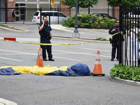 In this Sunday, May 28, 2017 photo, officials surround a U.S. Navy Seal's parachute that landed in a parking lot after the parachutist fell into the Hudson River when his parachute failed to open during a Fleet Week demonstration over the river in Jersey City, N.J. The Navy said the parachutist was pronounced dead at Jersey City Medical Center.