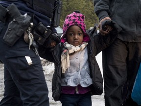 An young asylum claimant is held by an RCMP officer and her father after crossing the border into Canada from the United States, Tuesday, March 28, 2017 near Hemmingford, Que.