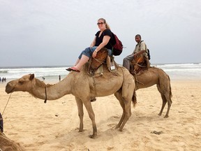 The author and her translator, Alpha Jallow, ride camels on the beach facing the Atlantic Ocean, near Lac Rose.