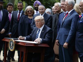 President Donald Trump signs an executive order aimed at easing an IRS rule limiting political activity for churches, Thursday, May 4, 2017, in the Rose Garden of the White House in Washington.