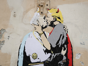 A poster showing Pope Francis kissing a devilish, gun-toting Donald Trump is seen on a wall in Rome on May 11, 2017. It is captioned in English and Italian with the words "The Good forgives the Evil" in tiny letters along Francis’ belt.