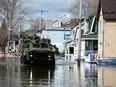 A military vehicle drives along a flooded street as waters breach the Gatineau River and flood the neighbourhood in Gatineau, Quebec on Wednesday, May 10, 2017.