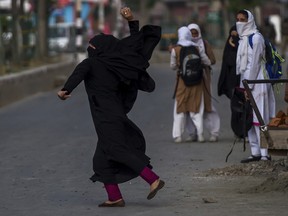 A burqa clad Kashmiri school girl throws stones at Indian paramilitary soldiers during a protest in Srinagar, Indian controlled Kashmir