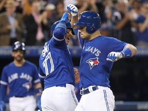 Luke Maile #22 of the Toronto Blue Jays is congratulated by Ryan Goins #17 after hitting a two-run home run in the fifth inning during MLB game action against the Cincinnati Reds at Rogers Centre on May 31, 2017 in Toronto, Canada.