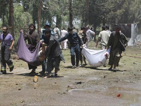Afghans carry the bodies of men at after a suicide car bombing in Helmand province southern of Kabul, Afghanistan, Thursday, June 22, 2017. The bomber struck outside a bank, targeting Afghan troops and government employees waiting to collect their salaries ahead of a major Muslim holiday and killing at least two dozen people, officials said. (AP Photo/Abdul Khaliq)