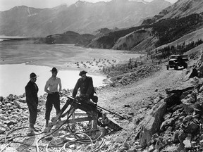 This 1942 photo provided by the U.S. Army Corp of Engineers Office of History and taken in the Northern Sector of the ALCAN Highway under construction shows 'Drifters' at work over a high piece of the ALCAN Route in the Yukon. The 'Drifter' is a pneumatic drilling device which makes the hole into which dynamite charges are later placed to blast the road. The highway's 75th anniversary is this year. (U.S. Army Corps of Engineers Office of History via AP)