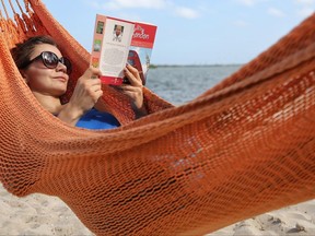 FILE - In this May 2, 2017, file photo, Kristiina Nurk, 34, enjoys a good book underneath the blue summer-like skies and weather as she vacations in Miami for a second day while on holiday. A new survey from The Associated Press-NORC Center for Public Affairs Research found that resting and relaxing is very or extremely important to three-fourths of Americans while on vacation. (Carl Juste/Miami Herald via AP, File)