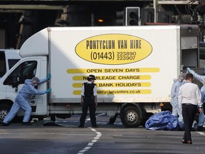 Forensic officers move the van at Finsbury Park in north London, where a vehicle struck pedestrians in north London Monday, June 19, 2017. The vehicle struck pedestrians near a mosque in north London early Monday morning. (AP Photo/Frank Augstein)