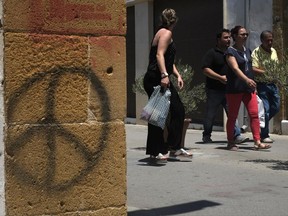 People cross the Ledra street crossing point that leads from the north to the south between the U.N buffer zone in the divided capital Nicosia, Cyprus, Wednesday, June 28, 2017. High-level envoys to a new round of talks aimed at reunifying the country's Greek and Turkish communities after 43 years arrived for the U.N.-sponsored discussions in the Swiss Alps. (AP Photo/Petros Karadjias)