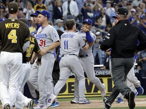 Los Angeles Dodgers manager Dave Roberts, center rear, is held back by third baseman Logan Forsythe (11) as the Dodgers and the San Diego Padres come onto the field during an argument in the second inning of a baseball game Friday, June 30, 2017, in San Diego. (AP Photo/Gregory Bull)