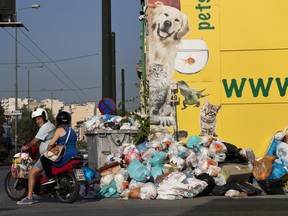 A motorcyclist looks on as he drives next to a pile of garbage in Piraeus, near Athens, on Monday, June 26, 2017. Municipality workers have been on strike for almost a week , hindering trash collection across the country. (AP Photo/Petros Giannakouris)