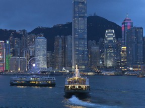 This June 20, 2017, photo, shows a general view of Victoria Peak and Central district over Victoria Harbor, in Hong Kong. Once known as Victoria after the British queen, Hong Kong island's waterfront formed the core of the British settlement after Hong Kong island was handed over as a colony in 1842. Today as Hong Kong approaches the 20th anniversary of its return to China, it remains a bustling commercial and financial center as well as the location of the main government offices. However, along the streets that angle sharply upward toward the mountains above, a more relaxed pace of life endures. (AP Photo/Kin Cheung)