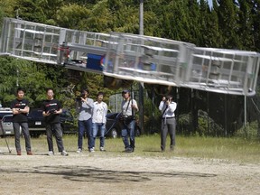 Tsubasa Nakamura, project leader of Cartivator, left, watches the flight of the test model of the flying car on a former school ground in Toyota, central Japan, Saturday, June 3, 2017 as another member, second from left, operates the remote control.