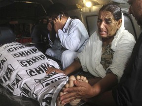 Mother of a police officer, who was killed by gunmen, mourns next to her son's body, carried into an ambulance at a hospital in Karachi, Pakistan, late Friday, June 23, 2017. Gunmen in the port city attacked police officers at a roadside restaurant and killed four of them before fleeing, according to senior police officer Asif Ahmed. (AP Photo/Fareed Khan)