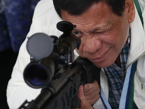 Philippine President Rodrigo Duterte checks the scope of a Chinese-made CS/LR4A sniper rifle during the presentation of thousands of rifles and ammunition by China to the Philippines Wednesday, June 28, 2017, at Clark Airbase in northern Philippines. According to a government statement the firearms form "part of the military aid package by China in relation with the emerging threat of terrorism and piracy in southern Philippines." (AP Photo/Bullit Marquez)