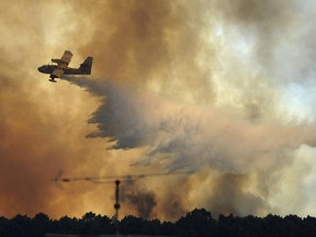 A fire fighting aircraft drops water over a fire outside the village of Pedrogao Grande central Portugal, Monday, June 19, 2017. More than 2,000 firefighters in Portugal battled Monday to contain major wildfires in the central region of the country, where one blaze killed dozens of people, while authorities came under mounting criticism for not doing more to prevent the tragedy. (AP Photo/Paulo Duarte)