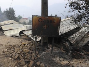 A burnt vehicle and farming tools by the side of a road in Casal de Alge, outside the village of Figueiro dos Vinhos central Portugal, Monday, June 19, 2017. More than 2,000 firefighters in Portugal battled Monday to contain major wildfires in the central region of the country, where one blaze killed 62 people, while authorities came under mounting criticism for not doing more to prevent the tragedy. (AP Photo/Paulo Duarte)