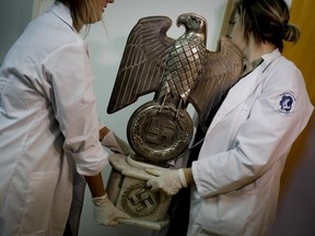 Members of the federal police carry a Nazi statue at the Interpol headquarters in Buenos Aires, Argentina, Friday, June 16, 2017. In a hidden room in a house near Argentina's capital, police discovered on June 8th the biggest collection of Nazi artifacts in the country's history. Authorities say they suspect they are originals that belonged to high-ranking Nazis in Germany during World War II. (AP Photo/Natacha Pisarenko)