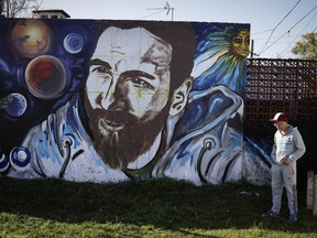 A man looks at graffiti of Lionel Messi painted near the house where the soccer star grew up in Rosario, Argentina, Friday, June 30, 2017. Some 260 guests, including teammates and former teammates of the Barcelona star, are expected to attend the highly anticipated wedding between Messi and Antonella Roccuzzo later Friday.(AP Photo/Victor R. Caivano)