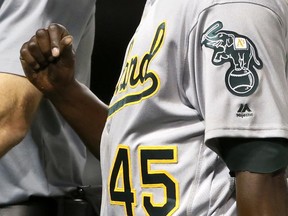 Oakland Athletics starter Jharel Cotton leaves a baseball game while looking at his pitching thumb with a member of the medical staff during the sixth inning of a baseball game against the Chicago White Sox, Friday, June 23, 2017, in Chicago. (AP Photo/Charles Rex Arbogast)
