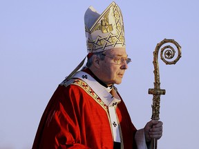 In this July 15, 2008, file photo, Cardinal George Pell walks onto the stage for the opening mass for World Youth Day in Sydney, Australia. Australian police say they are charging Pell with historical sexual assault offenses.