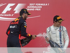 Red Bull driver Daniel Ricciardo of Australia, left, celebrates on the podium with third placed Williams driver Lance Stroll of Canada, after winning the Formula One Azerbaijan Grand Prix in Baku, Azerbaijan, Sunday, June 25, 2017. (AP Photo/Darko Bandic)