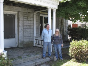 Brian and Joan Dumoulin pose on both sides of a marker showing the U.S.-Canadian border in the front yard of their home on June 8. She is in Canada, while he is in the United States.