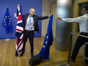 A member of protocol changes the EU and British flags prior to the arrival of EU Chief Brexit Negotiator Michel Barnier and British Secretary of State David Davis at EU headquarters in Brussels on Monday, June 19, 2017. Brexit negotiators will discuss Monday Britain's financial obligations to the European Union as the long, complicated and potentially perilous process of the U.K. leaving the bloc finally gets underway. (AP Photo/Virginia Mayo)