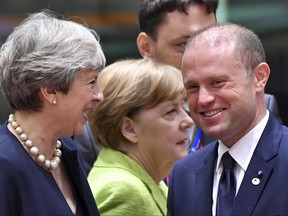 German Chancellor Angela Merkel, center, walks by as British Prime Minister Theresa May, left, speaks with Malta's Prime Minister Joseph Muscat, right, during a round table meeting at an EU summit in Brussels on Thursday, June 22, 2017. European Union leaders are gathering for a two day summit to weigh measures in which to tackle terrorism and migration and to create closer defense ties. (AP Photo/Geert Vanden Wijngaert)