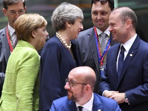 German Chancellor Angela Merkel, left, walks by as British Prime Minister Theresa May, center left, speaks with Malta's Prime Minister Joseph Muscat, right, during a round table meeting at an EU summit in Brussels on Thursday, June 22, 2017. European Union leaders are gathering for a two day summit to weigh measures in which to tackle terrorism and migration and to create closer defense ties. (AP Photo/Geert Vanden Wijngaert)
